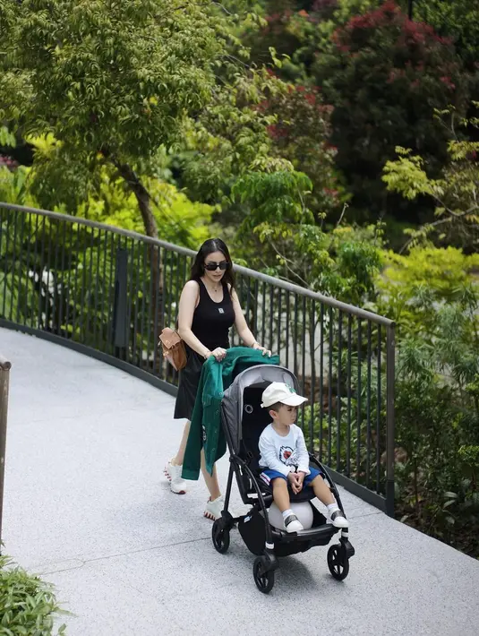 Kembali mendorong stroller sang buah hati, Momo Geisha tampil bergaya. Ia mengenakan dress selutut tanpa lengan berwarna hitam, dipadu kasual dengan sneakers putih, dan ia tampak menambahkan kesan kasual dengan mengenakan sunglasses. Foto: Instagram.