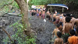 Warga Bali berjalan bersama menuju hutan manggrove untuk mandi lumpur tradisional atau yang dikenal sebagai Mebuug-buugan di desa Kedonganan, Bali (18/3). (AFP/Sony Tumbelaka)