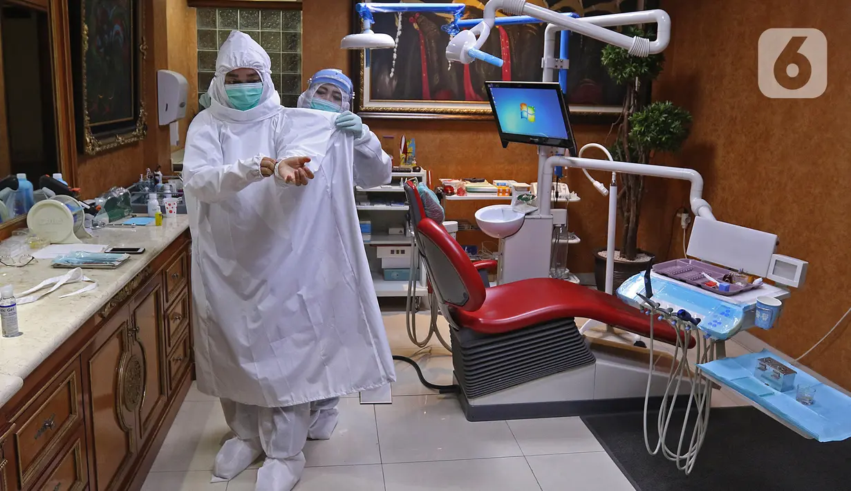 drg. Ayusha mengenakan alat perlindungan diri (APD) saat akan memeriksa pasien di salah satu klinik di kawasan Pulo Gadung, Jakarta, Rabu (22/4/2020). Penggunaan APD dilakukan sebagai SOP pemeriksaan gigi saat pandemi serta mengantisipasi penularan COVID-19. (Liputan6.com/Herman Zakharia)