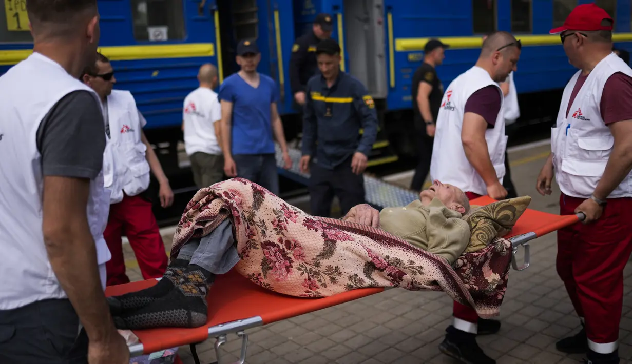 Seorang pasien lanjut usia digendong dengan tandu untuk menaiki kereta evakuasi medis yang dijalankan oleh MSF (Doctors Without Borders) di stasiun kereta api di Pokrovsk, Ukraina timur, Minggu (29/5/2022). Kereta tersebut dilengkapi dikelola oleh tenaga medis, dan mengangkut pasien dari rumah sakit yang kewalahan di dekat garis depan, ke fasilitas medis di Ukraina barat, jauh dari pertempuran. (AP Photo/Francisco Seco)