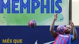 Dalam kesempatan tersebut, Memphis Depay menunjukkan kebolehannya mengolah si kulit bundar dihadapan awak media. (Foto: AFP/Lluis Gene)