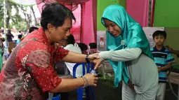 Warga mencelupkan jari ke tinta usai mencoblos ulang di TPS Utan Panjang, Jakarta, Minggu (19/2). Sebelumnya, ketua Bawaslu DKI Mimah Susanti memaparkan temuan adanya lima orang yang melanggar dalam pencoblosan, Rabu (15/2). (Liputan6.com/Faizal Fanani)