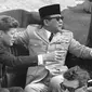 Presiden Amerika John Kennedy menunjuk Presiden Republik Indonesia Sukarno saat mereka duduk di mobil terbuka sesaat sebelum berangkat di Pangkalan Angkatan Udara Andrews, Washington, 24 April 1961. (AP Photo)