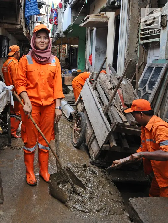 Petugas PPSU Kelurahan Kampung Melayu Siti Hajar berpose saat membersihkan sisa lumpur akibat banjir yang melanda Kebon Pala, Jakarta, Kamis (25/4). Siti Hajar (19) merupakan lulusan SMK yang baru 4 bulan bekerja menjadi pasukan oranye. (Liputan6.com/Herman Zakharia)