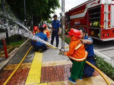 Petugas pemadam kebakaran mengajari anak-anak TK cara memadamkan api di Jakarta, Kamis (21/3). Kegiatan ini bertujuan mengenalkan profesi pemadam kebakaran dan memberi pengetahuan proses pemadaman api kepada anak usia dini. (merdeka.com/Imam Buhori)