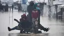 Puluhan hingga ratusan tenda pengungsi Palestina di wilayah tersebut terendam banjir. Bahkan, sebagian besar tenda pengungsi dilaporkan tidak lagi layak huni. Tampak dalam foto, warga Palestina menyeberangi jalan yang tergenang banjir setelah hujan lebat di Khan Younis, Jalur Gaza selatan, Kamis 11 Desember 2025. (AP Photo/Abdel Kareem Hana)
