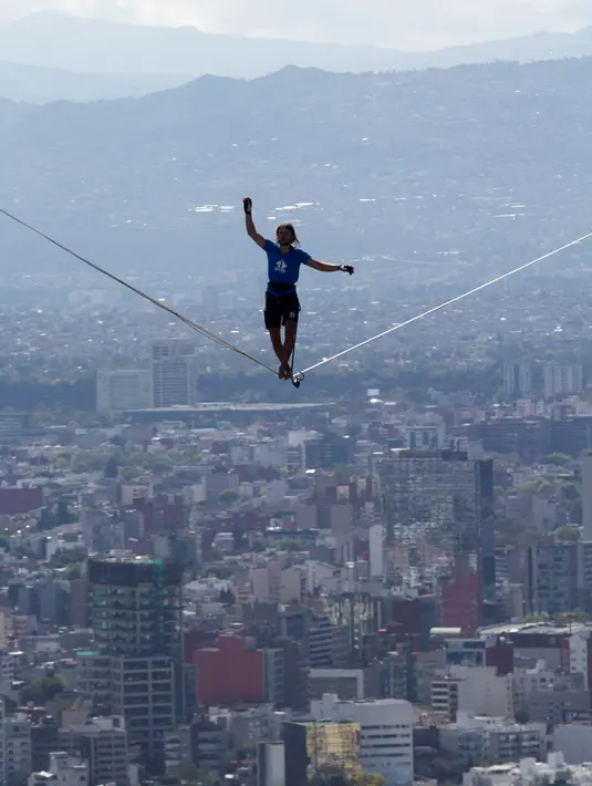 Alexander Schultz berjalan di atas tali sepanjang 217 meter yang menghubungkan dua gedung tertinggi Mexico City di Meksiko, 4 Desember 2016. Schultz butuh lima kali upaya menaklukkan tali yang dipasang pada ketinggian 246 meter tersebut (REUTERS/Stringer)