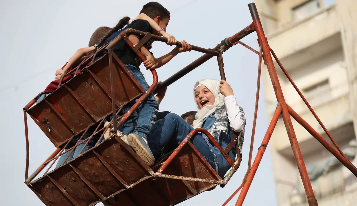 Anak-anak Suriah bermain di taman darurat selama perayaan Idul Fitri, hari libur Muslim yang dimulai pada akhir bulan puasa Ramadan, di Binnish di provinsi Idlib, Suriah barat laut yang dikuasai pemberontak, (26/5/2020). (AFP Photo/Omar Haj Kadour)