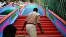 Pekerja menaiki tangga 272 langkah yang baru dicat, jalan untuk menuju kuil Batu Caves di Kuala Lumpur, Malaysia, 30 Agustus 2018. Meski ditentang, turis yang mengunjungi Batu Caves memuji warna yang dihadirkan. (AFP/Manan VATSYAYANA)