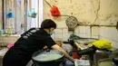 Wong Mei-ying (70) mengenakan masker sebagai tindakan pencegahan terhadap coronavirus novel COVID-19, saat ia membersihkan bagian dapurnya di flat yang terbagi di New Territories of Hong Kong, 14 Mei 2020. (AFP/Anthony Wallace)