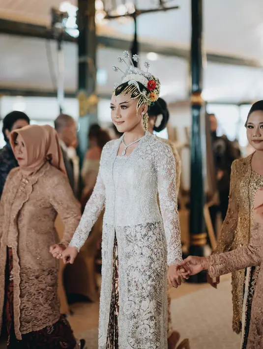 Kebaya pernikahan Erina lainnya yang wajib disimak adalah kebaya yang dikenakannya di momen akad. Kebaya putih panjang ini memiliki motif brokat floral yang sangat cantik. Foto: Instagram.
