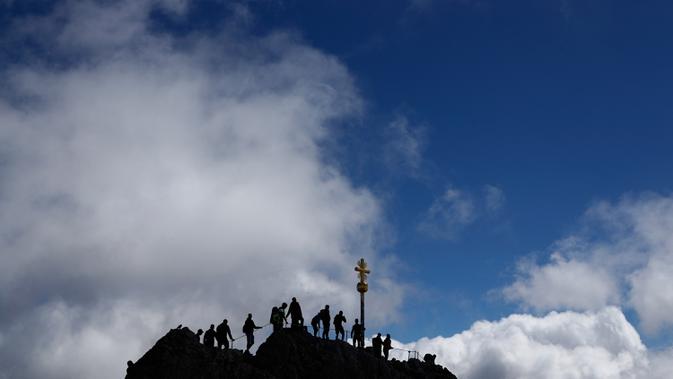 Orang-orang mengantre untuk mencapai puncak salib di puncak gunung tertinggi Jerman, Zugspitze, dekat Garmisch-Partenkirchen, Jerman pada 19 Agustus 2020. Setiap tahunnya gunung dengan ketinggian 2.962 meter tersebut membuat sekitar setengah juta pengunjung terpesona. (AP Photo/Matthias Schrader)