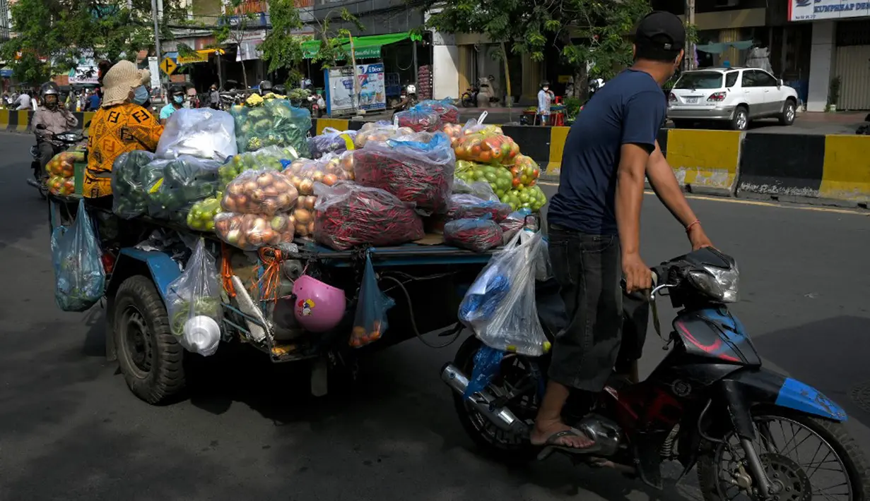 Seorang pedagang mengendarai kereta motornya yang berisi sayuran untuk dijual karena pasar tetap ditutup di tengah pembatasan lockdown yang diberlakukan untuk mencoba menghentikan lonjakan kasus virus corona COVID-19 di Phnom Penh, Kamboja, Selasa (11/5/2021). (TANG CHHIN Sothy/AFP)