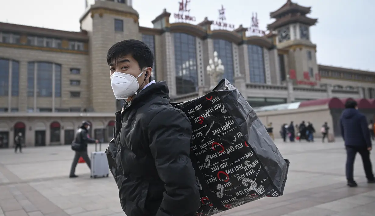 Seorang pria membawa tasnya berjalan ke pintu masuk stasiun kereta api Beijing di ibu kota China (7/1/2023). Ketika migrasi tahunan dimulai dengan orang-orang yang kembali ke kampung halaman mereka untuk perayaan Tahun Baru Imlek. (AFP/Wang Zhao)