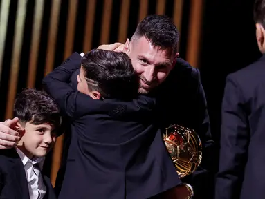 Pemain Inter Miami, Lionel Messi, dipeluk anaknya saat menerima penghargaan Ballon d'Or di Theatre du Chatelet, Paris, Selasa (31/10/2023). La Pulga berhasil menyabet penghargaan Ballon d'Or 2023 atau yang kedelapan sepanjang kariernya. (AFP/Franck Fife)