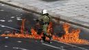 Polisi anti huru-hara melwati jalanan yang terbakar api di Athena, Yunani, (12/11/2015). Para Demonstran juga melakukan aksi mogok kerja selama 24 jam. (REUTERS/Yannis Behrakis)