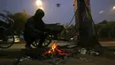 Mereka menghangatkan diri di sekitar api yang membara yang dibangun dari sampah dan kotak kardus yang dibuang. (Money SHARMA / AFP)