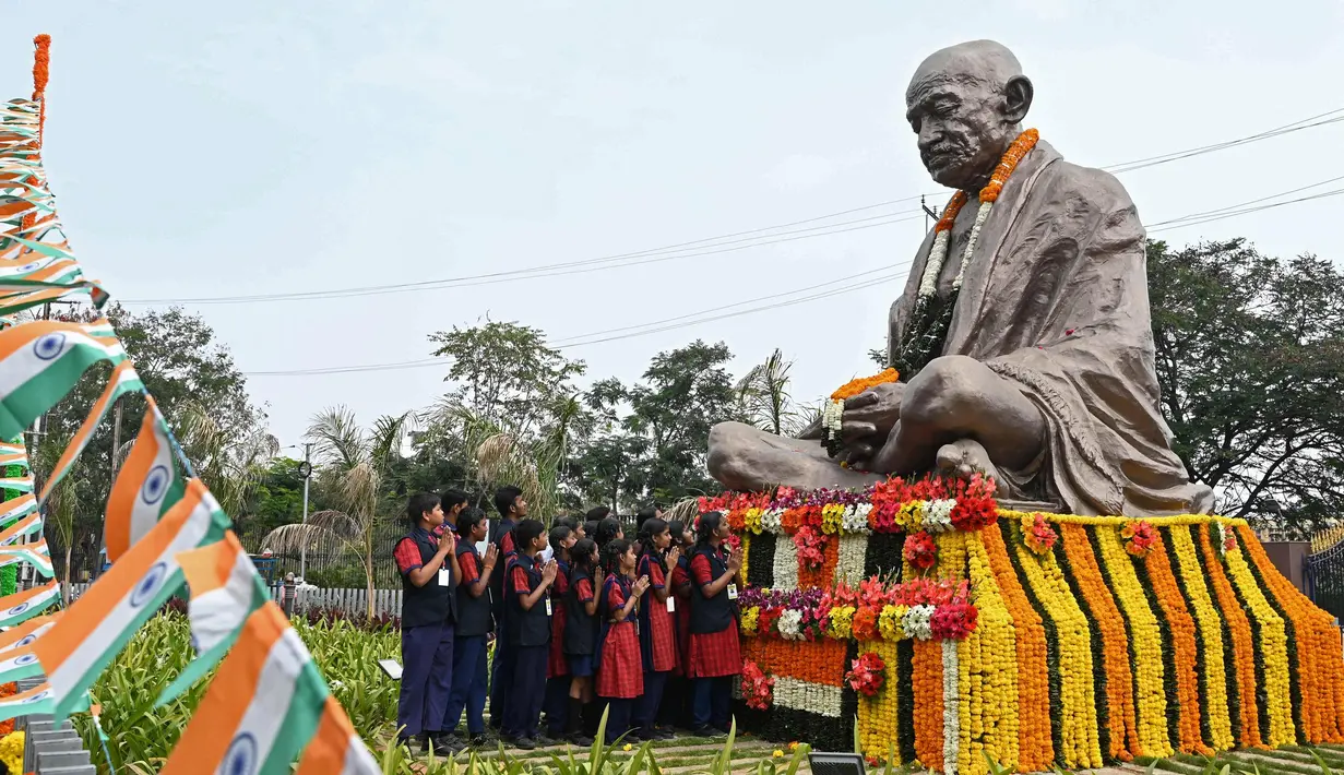 Sejumlah siswa sekolah menaburkan bunga pada patung Mahatma Gandhi pada hari peringatan kematiannya di Hyderabad, India, Senin (30/1/2023). Pada 30 Januari 1948, pemimpin spiritual dan gerakan politik kemerdekaan India Mahatma Gandhi tewas terbunuh. Mahatma Gandhi tewas ditembak oleh seorang ekstremis Hindu Nathuram Godse. (NOAH SEELAM/AFP)