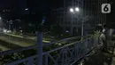 Warga melihat suasana jalan lengang kawasan Sudirman, Jakarta, Rabu (12/5/2021) malam. Polda Metro Jaya memberlakukan crowd free night untuk mencegah kerumunan takbir keliling di malam Idul Fitri 1442 yang berlaku mulai pukul 22:00 malam ini. (Liputan6.com/Herman Zakharia)