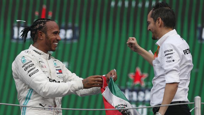 Pembalap Mercedes dari Inggris, Lewis Hamilton berselebrasi dengan anggota tim Marcelo Martinelli setelah berhasil menjuarai balapan GP Meksiko di Autodromo Hermanos Rodriguez, Mexico City (28/10/2019). (AP Photo/Rebecca Blackwell)