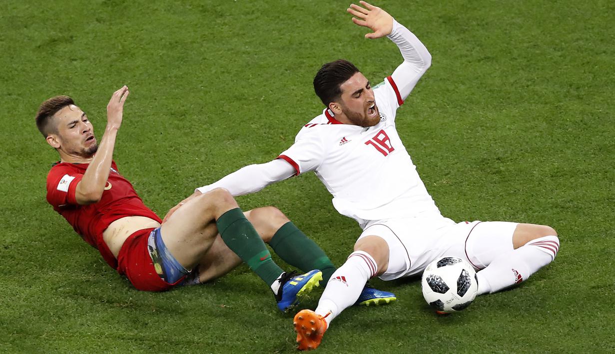 Pemain Portugal, Raphael Guerreiro (kiri) berebu bola dengan pemain Iran, Alireza Jahanbakhsh pada laga grup B Piala Dunia 2018 di Mordovia Arena, Saransk, Rusia, (25/6/2018). Portugal dan Iran bermain imbang 1-1. (AP/Darko Bandic)