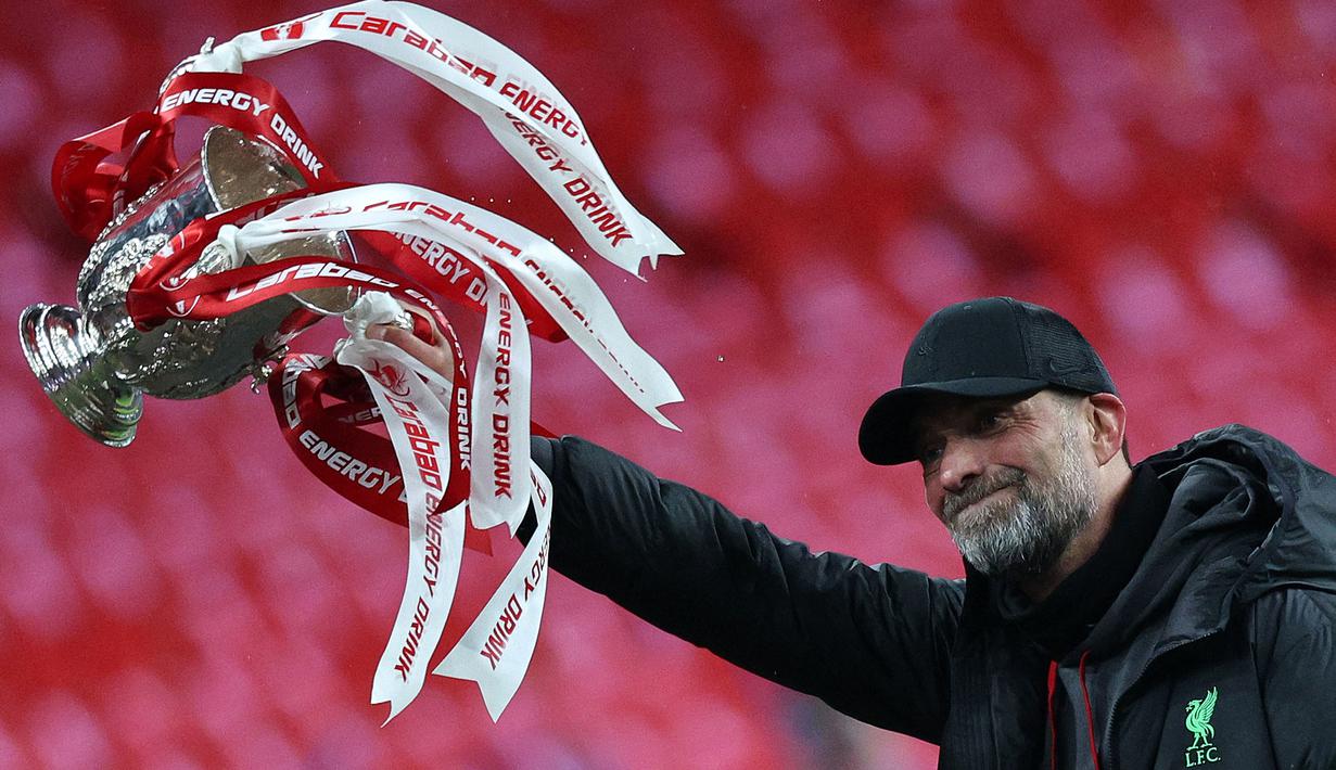 Ekspresi bahagia pelatih Liverpool, Jurgen Klopp saat mengangkat trofi Carabao Cup 2023/2024 di Stadion Wembley, Inggris, Minggu (25/02/2024). The Reds menang atas Chelsea dengan skor 1-0 melalui gol Virgil Van Dijk pada menit ke-118. (AFP/Adrian Dennis)