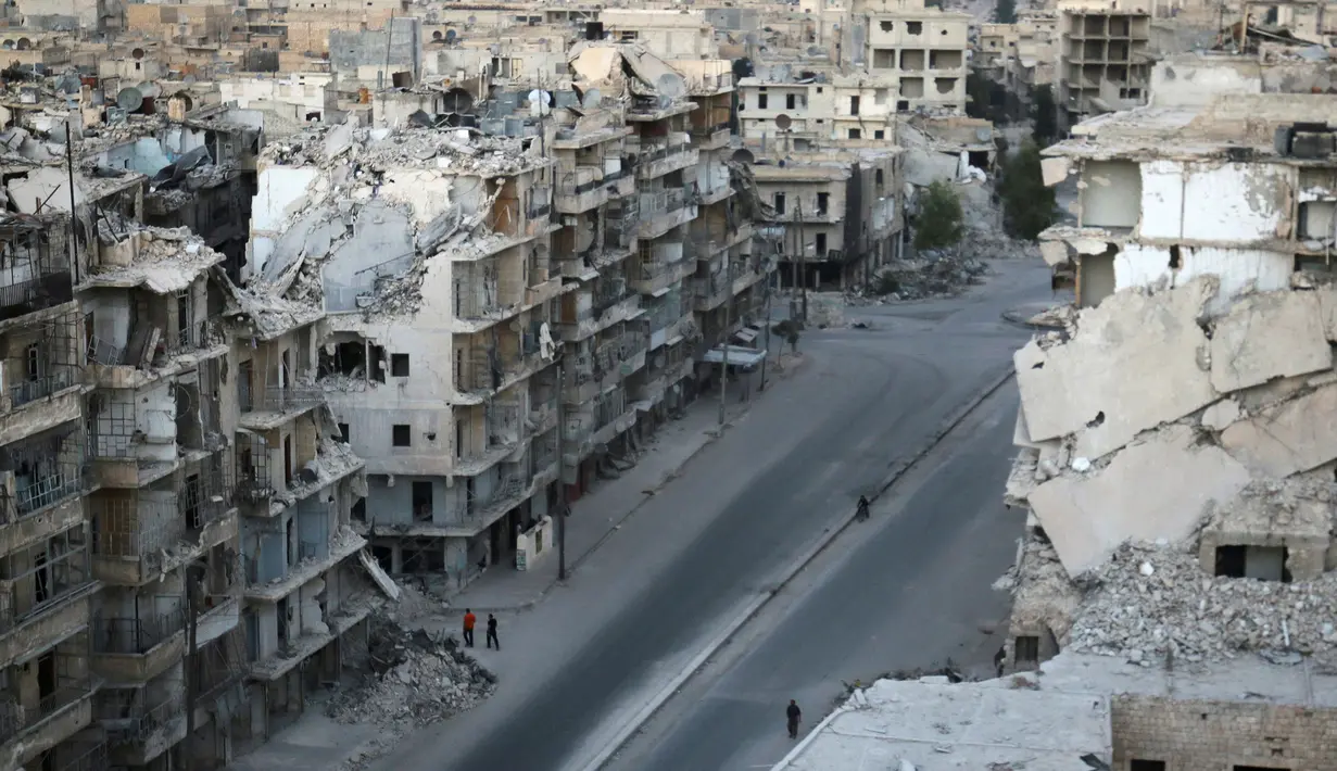 Sejumlah orang berjalan melewati bangunan yang hancur akibat pertempuran di Tariq al-Bab yang dikuasai pemberontak di Aleppo, Suriah, (5/10). PBB memperkirakan 275.000 orang terperangkap dalam pertempuran tersebut. (REUTERS/Abdalrhman Ismail)