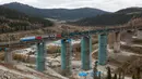 Kereta melintas di atas jembatan rel yang dalam proses penyelesaian di Taiga, dekat stasiun Dzheb, Krasnoyarsk, Rusia, 10 Oktober 2016. Lokasi proyek Trans-Siberian Railway ini dikelilingi pemandangan pegunungan dan hutan cemara. (REUTERS/Ilya Naymushin)