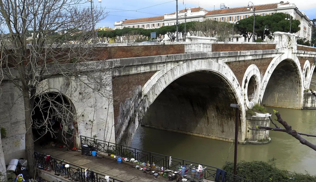 Sejumlah barang milik tunawisma terlihat di kawasan permukiman kumuh bawah jembatan di Sungai Tiber, Roma, Italia (13/4). Para tunawisma menggunakan kayu, karton, hingga terpal plastik untuk membuat tenda sebagai tempat tinggalnya. (REUTERS / Max Rossi)