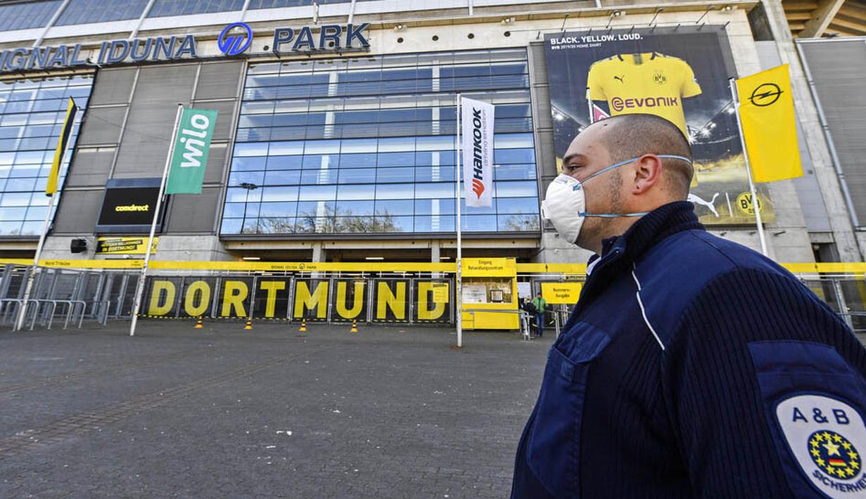 Petugas Keamanan dengan menggunakan masker berjaga di depan Stadion Signal Iduna Park, Jerman, Sabtu (4/4/2020). Stadion Borussia Dortmund ini dialihfungsikan menjadi tempat pusat pengujian COVID-19. (AP/Martin Meissner)