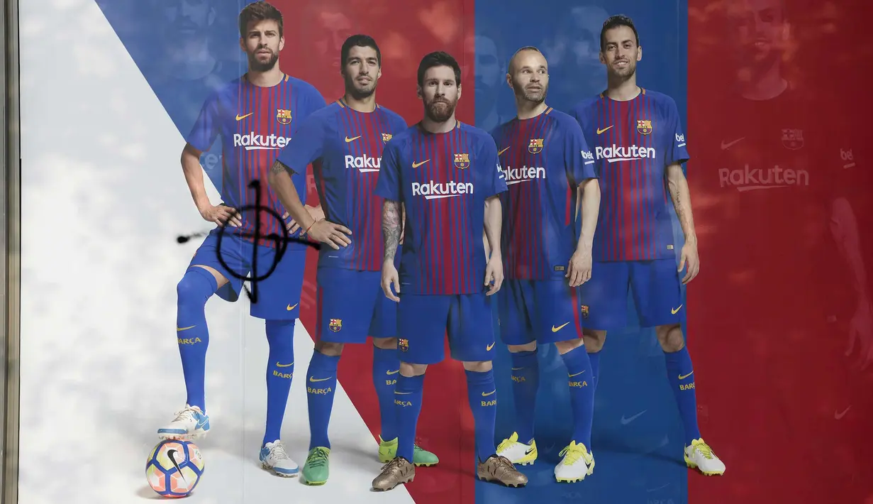 Poster Gerard Pique (kiri) yang dirusak di sebuah toko di luar stadion Camp Nou, Barcelona (3/10). Pique ikut memberikan suaranya saat referendum diadakan pada Minggu (1/10/2017) lalu. (AFP Photo/Josep Lago)