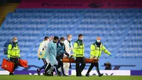 Petugas medis dalam APD lengkap membawa pemain Manchester City Eric Garcia yang cedera saat menghadapi Arsenal pada laga Premier League di Etihad Stadium, Manchester, Inggris, Rabu (17/6/2020). Manchester City menang dengan skor 3-0. (LAURENCE GRIFFITHS/POOL/AFP)