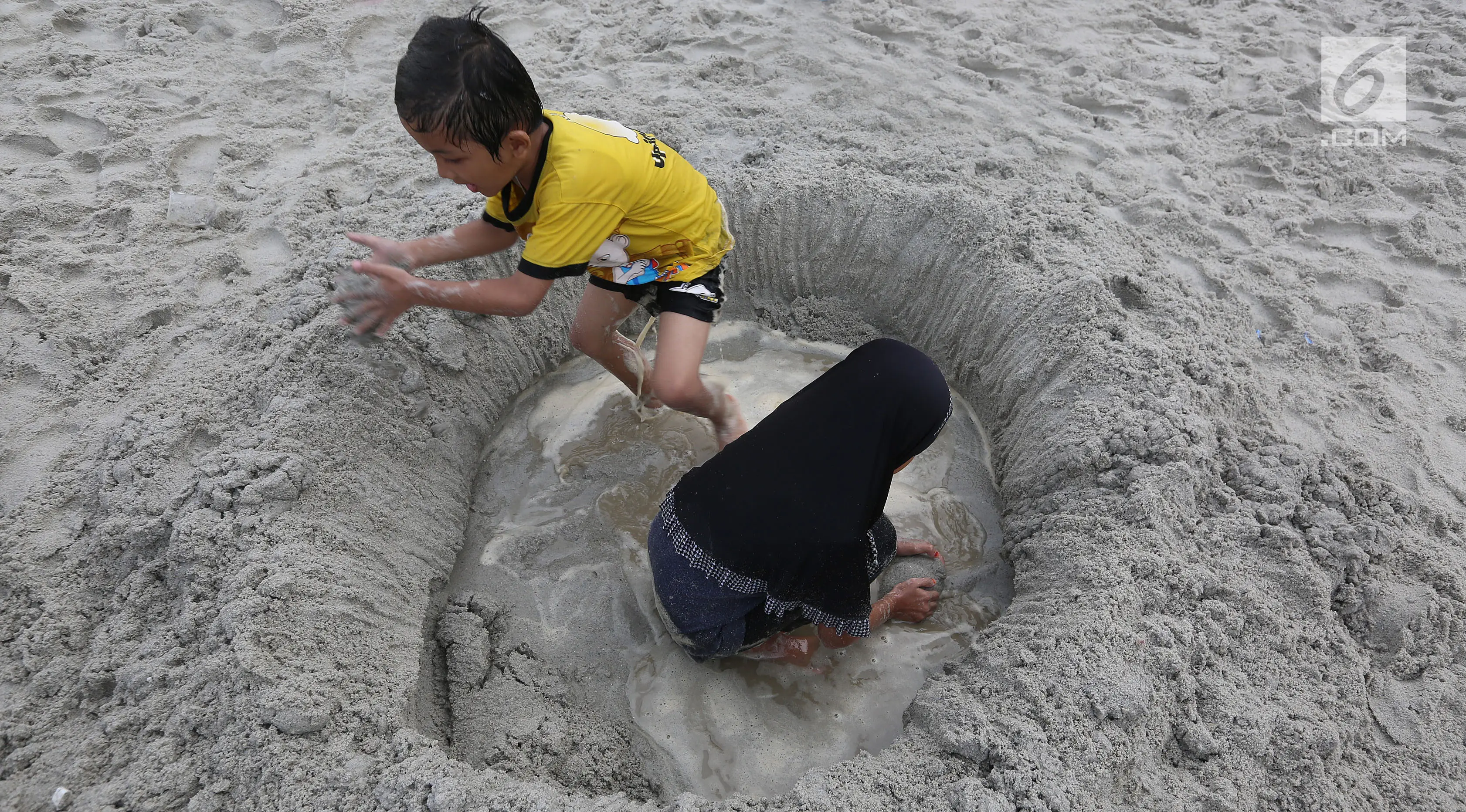 Anak-anak bermain pasir di Pantai Ancol, Jakarta, Senin (26/6). Memasuki hari kedua lebaran Warga memanfaatkan liburnya bersama keluarga bertamasya ke tempat-tempat wisata yang ada di Jakarta kususnya Ancol. (Liputan6.com/Johan Tallo)