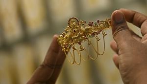 Seorang pelanggan memegang perhiasan emas selama festival Hindu 'Akshaya Tritiya', hari keberuntungan dalam kalender Hindu untuk membeli barang-barang berharga, di ruang pamer perhiasan di Chennai, India, Selasa (3/5/2022). Membeli emas adalah kegiatan yang populer di Akshaya Tritiya, karena ini adalah simbol utama kekayaan dan kemakmuran. (Arun SANKAR / AFP)