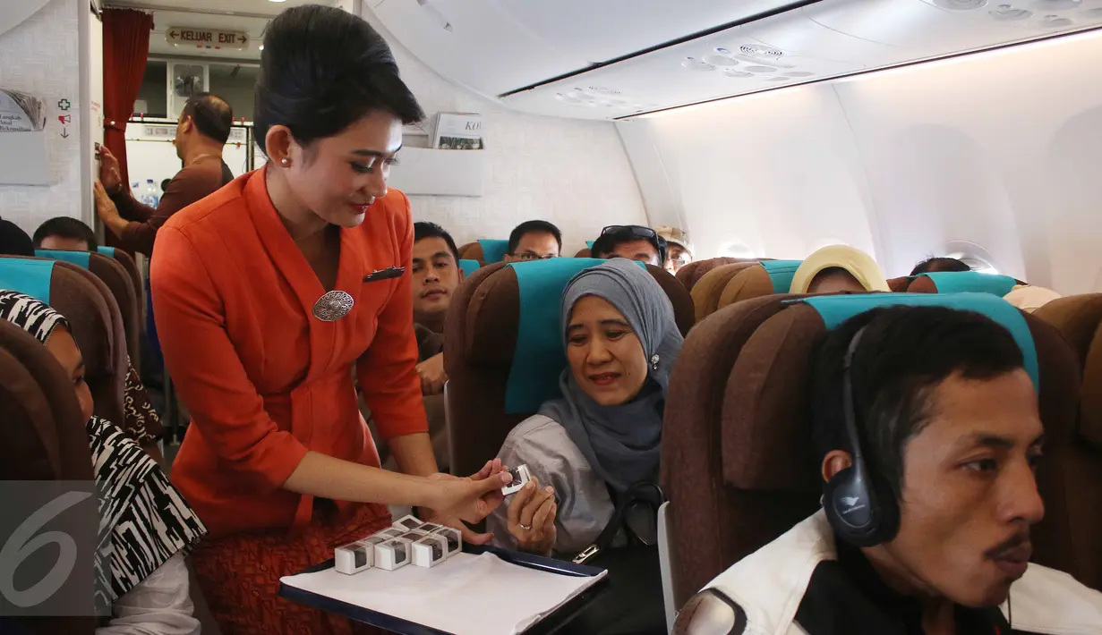 Pramugari membagikan cokelat kepada penumpang dalam penerbangan di Pesawat Garuda Indonesia menuju, Padang, Sumatera Barat, Jumat (21/4). Dalam rangka menyambut Hari Kartini, penerbangan Garuda Indonesia diawaki oleh perempuan. (Liputan6.com/Angga Yuniar)