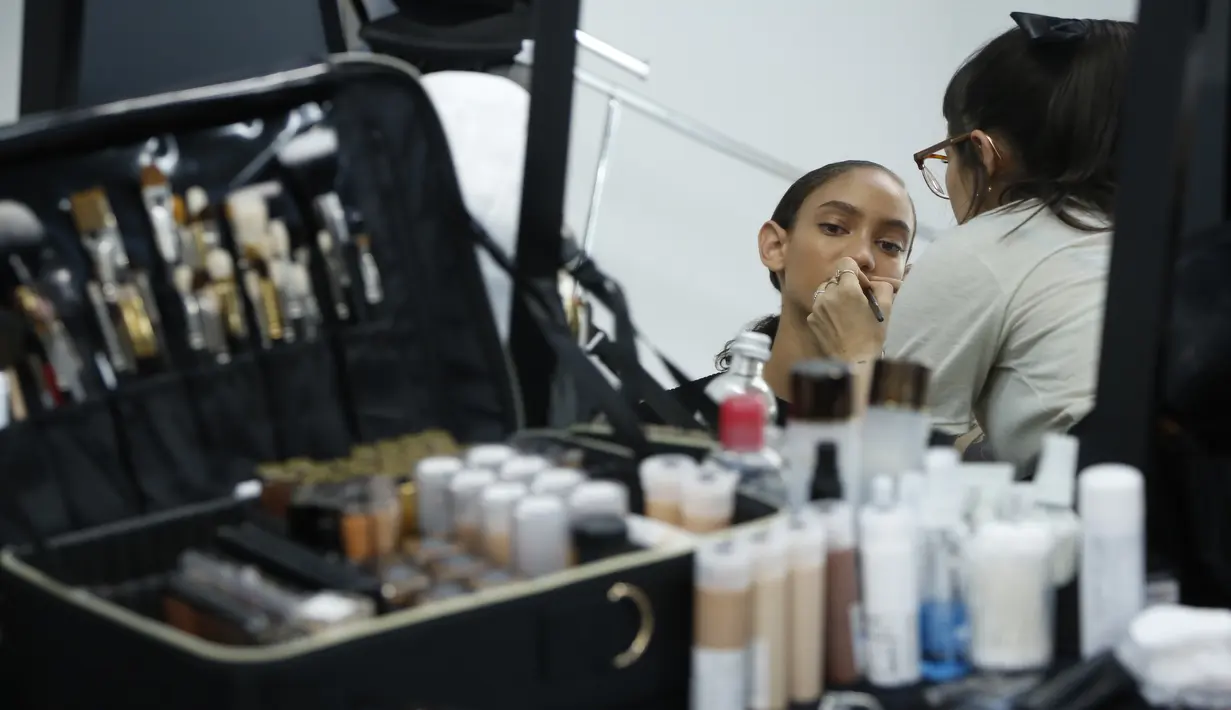 Model saat dirias di belakang panggung sebelum memamerkan koleksi busana wanita Fall Winter 2020 Jil Sander selama Fashion Week di Milan, Italia, Rabu, (19/2/2020). (AP Photo/Domenico Stinellis)