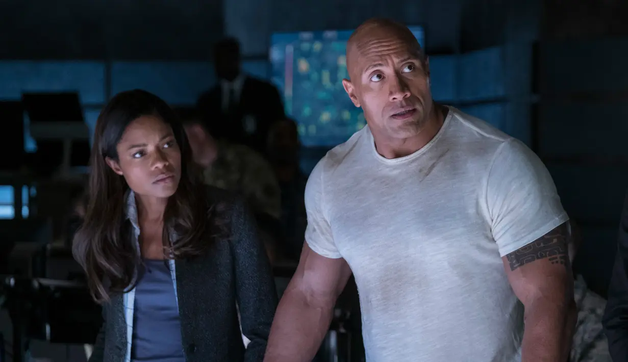 Naomi Harris (kiri) dan Dwayne Johnson alias The Rock dalam adegan film Rampage. Dalam film ini Naomie berperan sebagai ahli genetik bernama Dr Kate Caldwell. (Frank Masi/Warner Bros via AP)