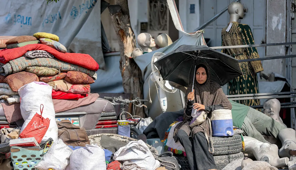 Seorang wanita duduk di samping barang-barang yang diselamatkan dari puing-puing Menara Prajurit Tak Dikenal di kawasan Rimal, Kota Gaza, pada 15 September 2025. (Omar AL-QATTAA/AFP)