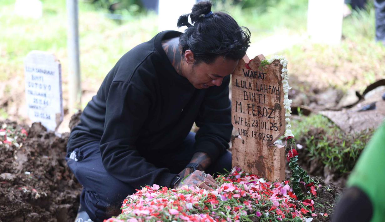 Konten kreator yang juga musisi, Reza Oktovian atau lebih dikenal dengan panggilan Reza Arap tertunduk di sisi nisan kekasihnya, Lula Lahfah, di Tempat Pemakaman Umum (TPU) Rawa Terate, Cakung, Jakarta Timur, pada Sabtu (24/1/2026). Selebgram Lula Lahfah dimakamkan di Tempat Pemakaman Umum (TPU) Rawa Terate, Cakung, Jakarta Timur, pada Sabtu (24/1/2026). (Kapanlagi.com/Budy Santoso)