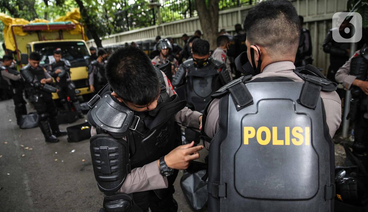 Personel Brimob bersiap mengenakan perlengkapan pelindung diri di Kawasan Bundaran HI, Jakarta, Selasa (13/10/2020). Sebanyak kurang lebih 12 ribu personel gabungan TNI, Polri dan Pemprov DKI Jakarta diterjunkan mengawal aksi tolak Undang-Undang Cipta Kerja Omnibus Law. (Liputan6.com/Faizal Fanani)