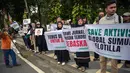 Seorang pekerja menyapu jalan saat para aktivis mengadakan unjuk rasa menentang pencegatan kapal-kapal yang berpartisipasi dalam armada Global Sumud Flotilla (GSF), sebuah misi bantuan kemanusiaan ke Gaza melalui jalur laut, di Surabaya, Jawa Timur pada Kamis 21 Mei 2026. (JUNI KRISWANTO/AFP)