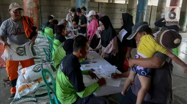 Petugas mengecek data warga penerima Bantuan Sosial (Bansos) cadangan Beras Pemerintah (CBP) di kawasan Warakas, Tanjung Priok, Jakarta Utara, Selasa (20/2/2024). (Liputan6.com/Herman Zakharia)