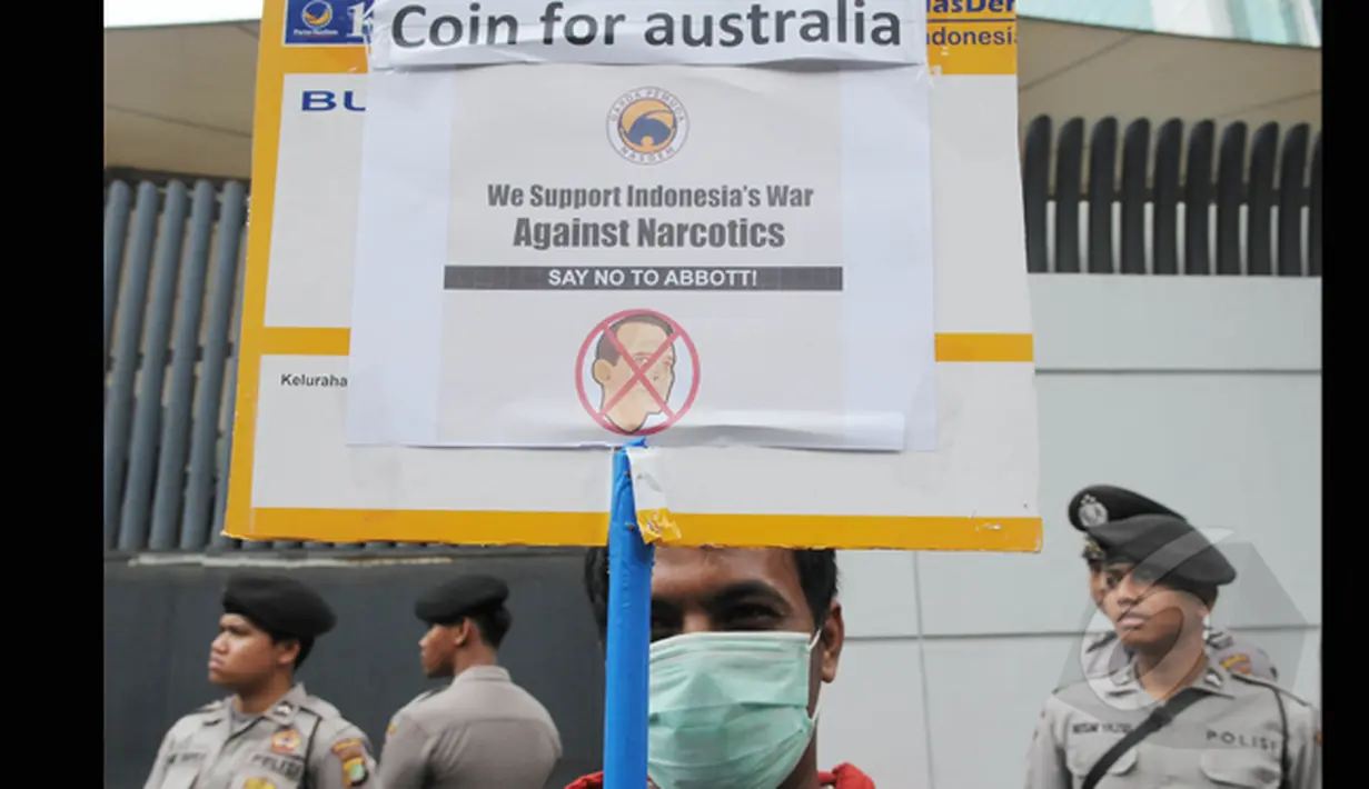 Anggota Garda Pemuda Nasdem membawa poster bergambar Tonny Abbott saat menyerahkan ribuan koin untuk PM Tony Abbot di depan kantor Kedutaan Besar Australia, Jakarta, Jumat (27/2/2015). (Liputan6.com/Herman Zakharia)