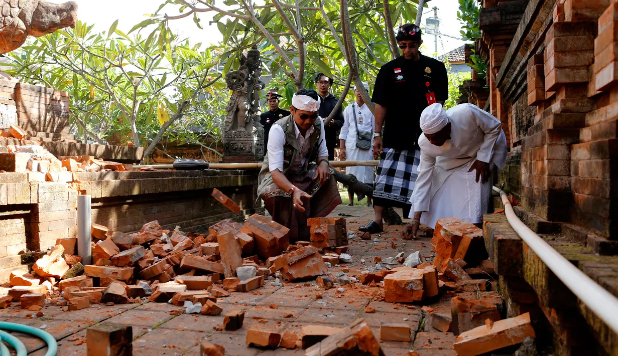 Pemuka agama memantau kerusakan pada bagian candi yang runtuh akibat gempa di Pura Lokanatha, Denpasar, Bali, Selasa (16/7/2019). Gempa Magnitudo 5,8  yang mengguncang Bali tidak menimbulkan korban jiwa, tapi sejumlah bangunan di beberapa kawasan mengalami kerusakan. (AP/Firdia Lisnawati)