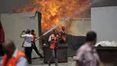 Beberapa petugas pemadam kebakaran Palestina berusaha memadamkan api di gudang PBB setelah serangan militer Israel di barat kota Gaza, (12/7/2014). (AFP PHOTO/Mahmud Hams)