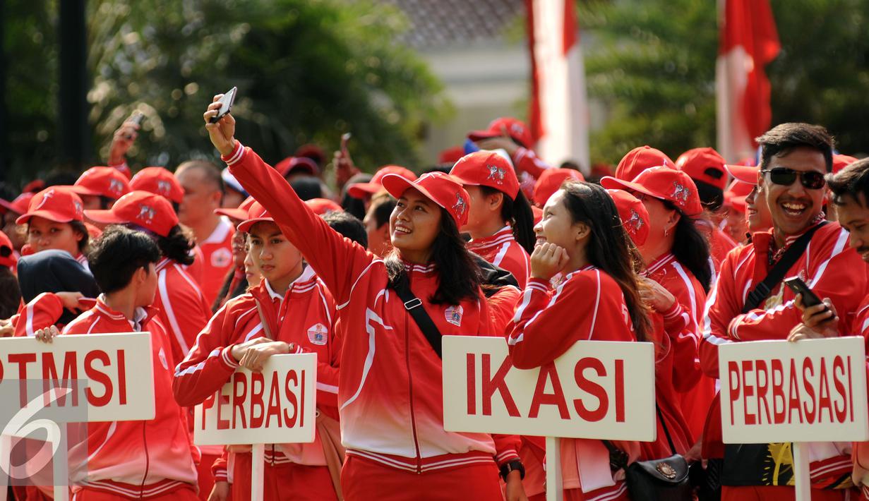 Salah satu atlet yang akan berlaga di PON XIX Jabar berselfie jelang upacara pelepasan di halaman Balaikota Jakarta, Rabu (7/9). Kontingen yang berangkat terdiri dari 915 atlet, 343 ofisial dan 62 ekstra ofisial. (Liputan6.com/Helmi Fithriansyah)