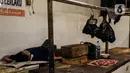 Seorang pria tidur di los daging non halal di Pasar Senen, Jakarta, Senin (13/9/2021). Manajer Umum dan Humas Perumda Pasar Jaya Gatra Vaganza mengatakan pihaknya sudah memanggil dan memberi sanksi administrasi kepada pedagang daging anjing di Pasar Senen Blok III tersebut (Liputan6.com/Johan Tallo)