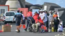 Beberapa orang pingsan karena kelelahan dan dibantu oleh staf Palang Merah. Satu orang ditandu dengan kursi roda saat para turis makan di teras restoran yang berjarak hanya beberapa meter. (STRINGER / AFP)