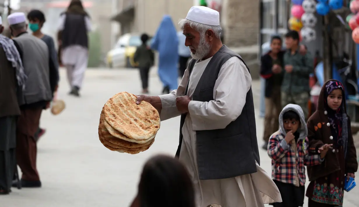 Seorang pria membawa roti gratis dari kota selama lockdown untuk mencegah penyebaran virus corona, pada bulan suci Ramadan di Kabul, Afghanistan (4/5/2020). Muslim di seluruh dunia sedang menjalankan Ramadan, ketika mereka menahan diri dari makan, minum dari subuh hingga senja. (AP/Rahmat Gul)