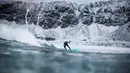 Aksi seorang peselancar diantara hamparan bukit es dan hawa dingin di Lofoten Islands, Norwegia, (10/3/2018). Suhu udara minus 13°C dan suhu diatas air sekitar 4°C. (AFP/Oliver Morin)